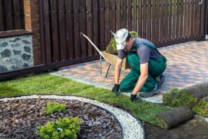 Homeowner tending drought-tolerant plants and raised vegetable beds in a modern backyard garden.